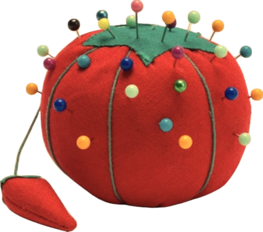 A tomato-shaped pin cushion with multicolored pins sticking out of it.